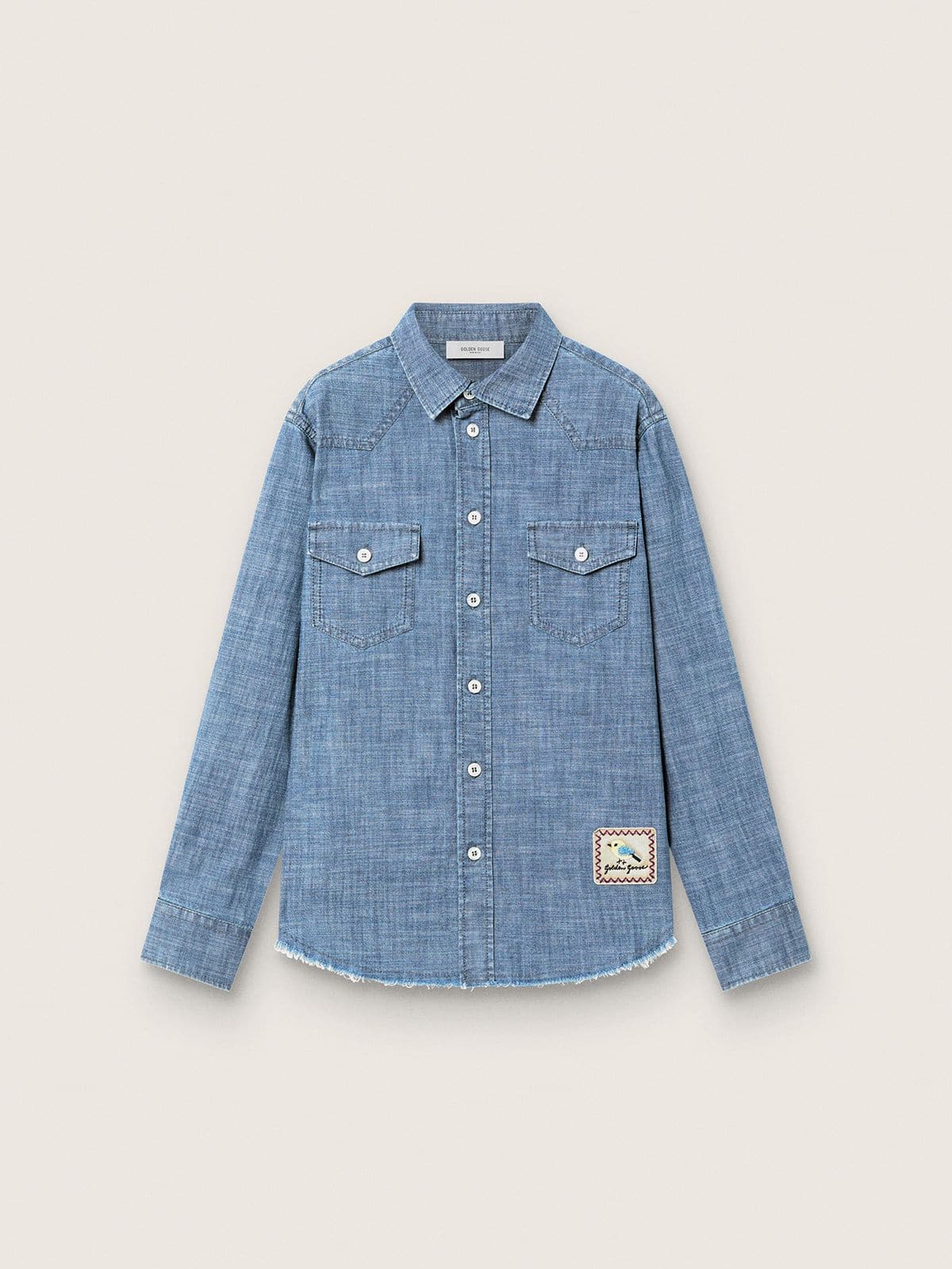 7fe2c774b43952002f63f6269ab5f2332db0b9c9df4bc5ff3e7495122f3f7a3a Journey unisex shirt in light blue cotton chambray with fringed hem and embroidered patch - Image 1